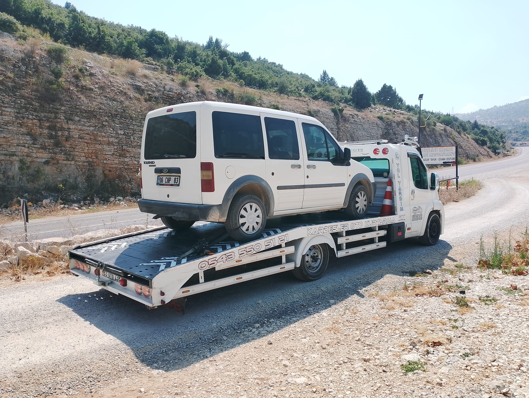 Virajlı yolda çekici üzerinde taşınan beyaz hafif ticari araç — Kardeşler Oto Kurtarma