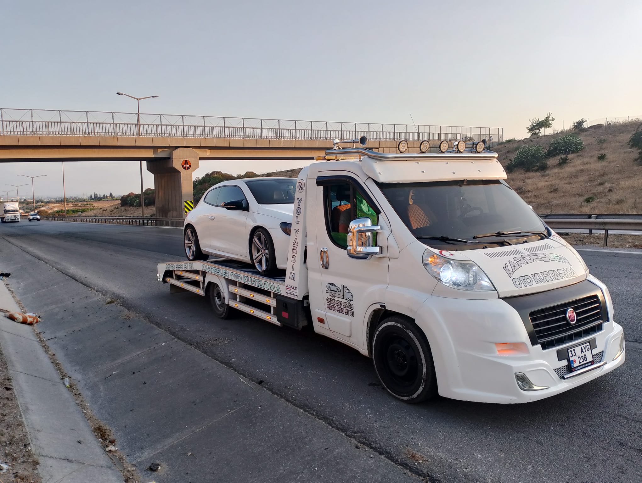 Üst geçit yakınında beyaz otomobil taşıyan çekici — Kardeşler Oto Kurtarma