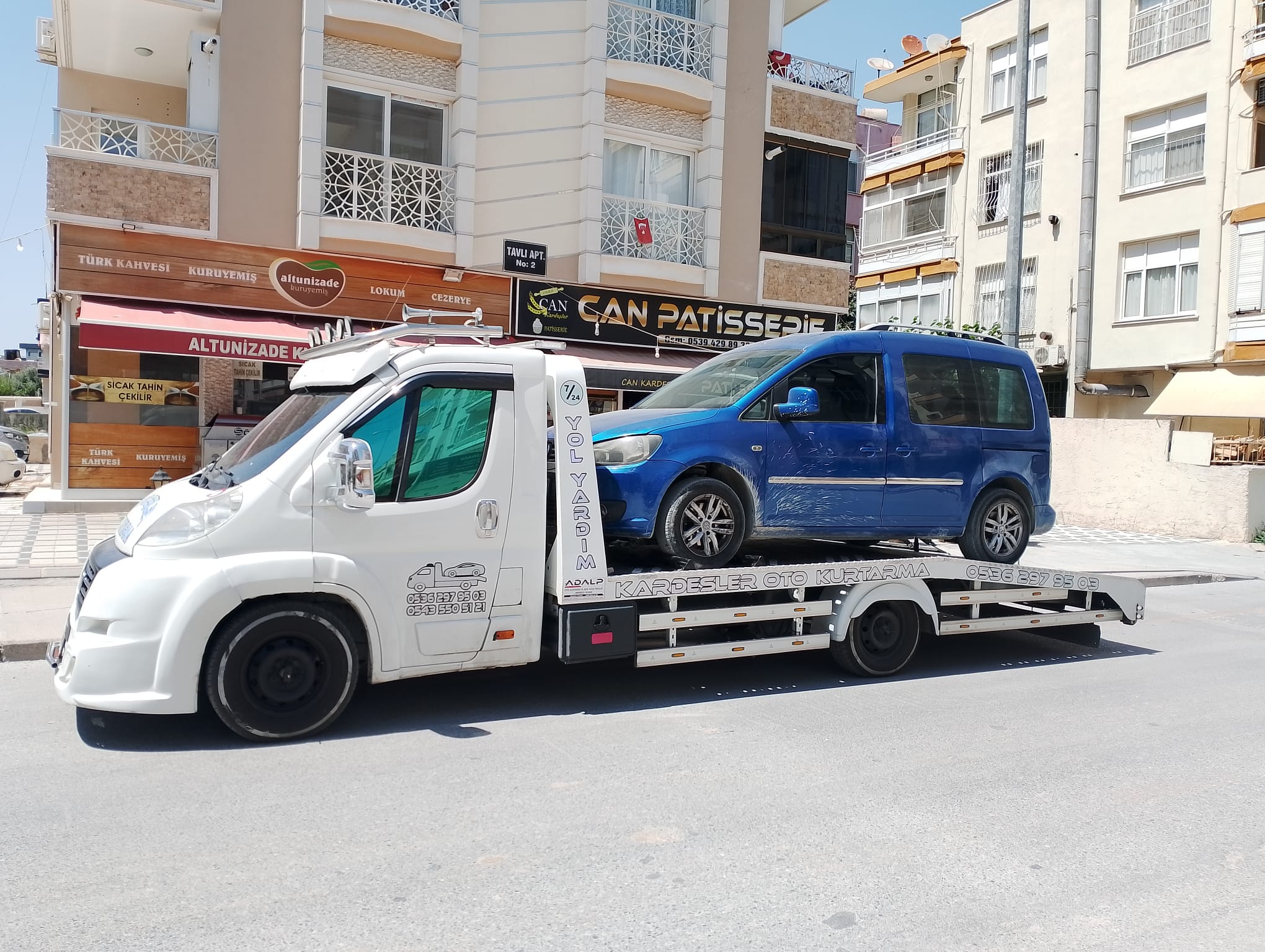Şehir içinde mavi hafif ticari araç taşıyan Kardeşler Oto Kurtarma çekicisi