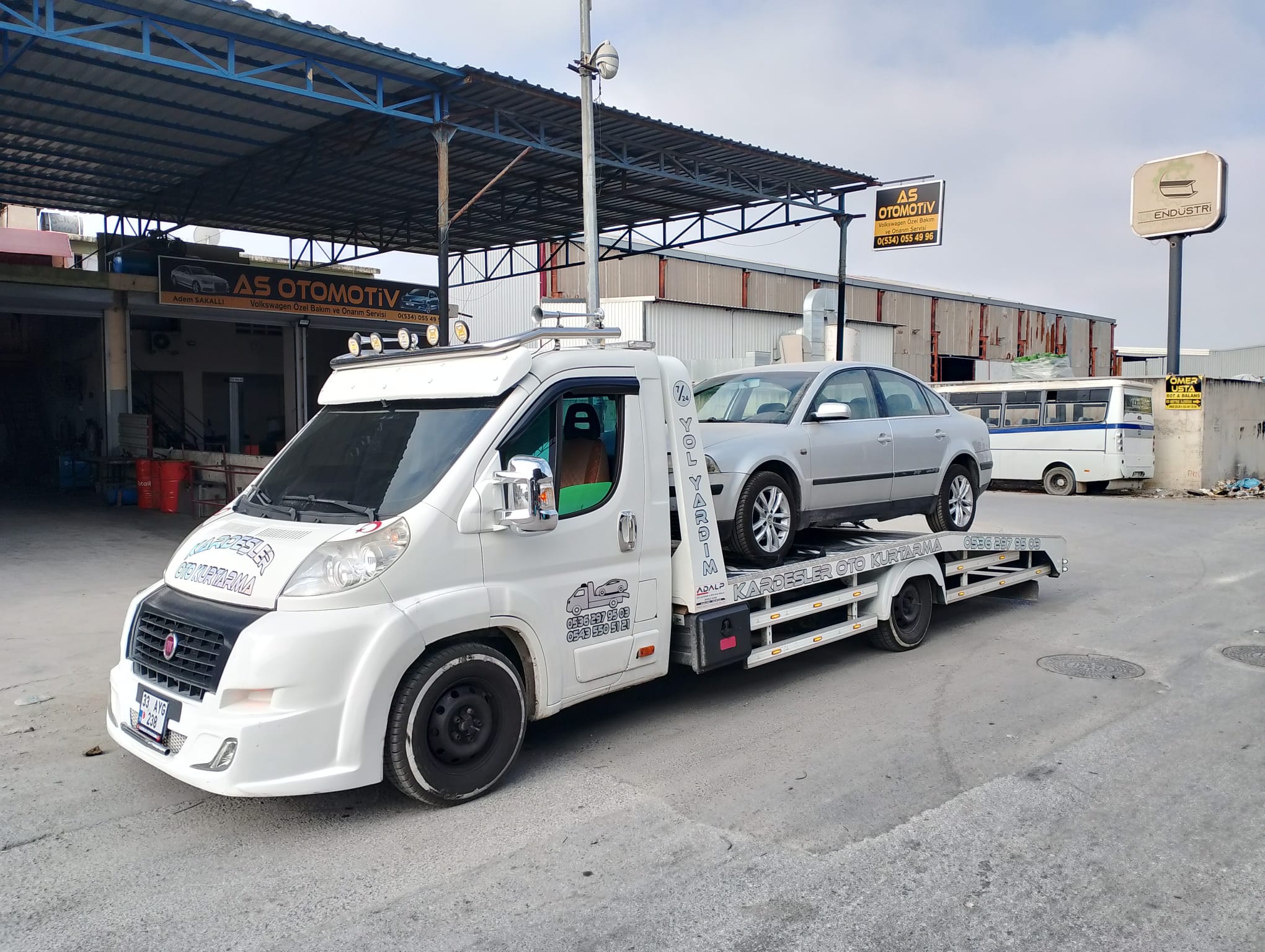 Oto servis önünde gri sedan yüklü çekici — Kardeşler Oto Kurtarma