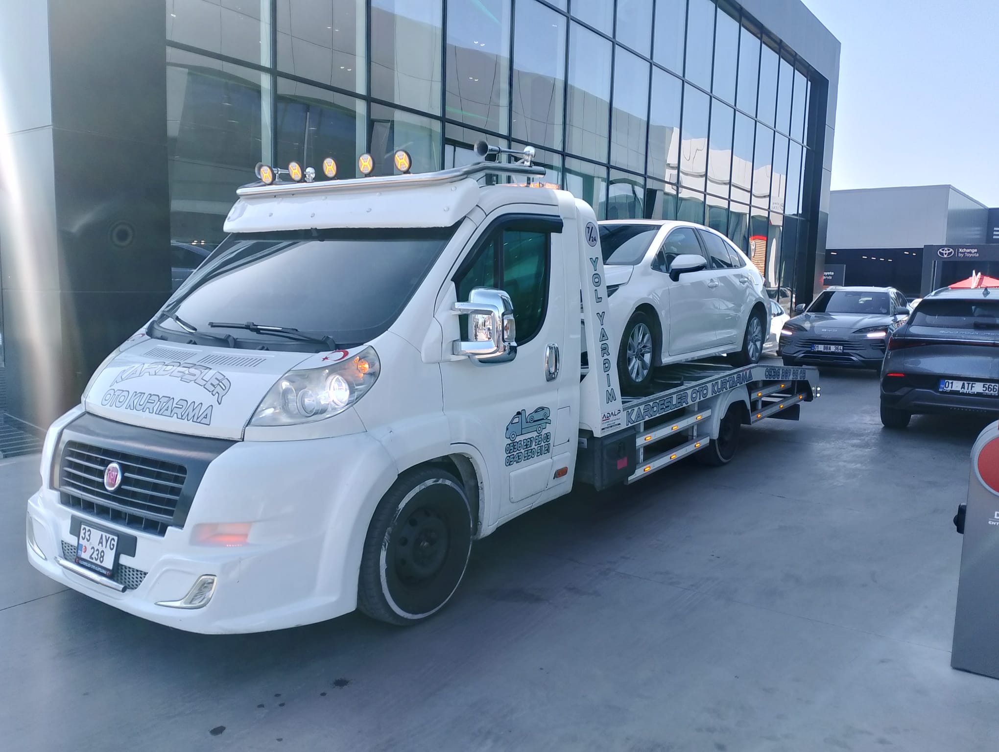 Cam cepheli bayi önünde çekiciye yüklenmiş beyaz otomobil — Kardeşler Oto Kurtarma